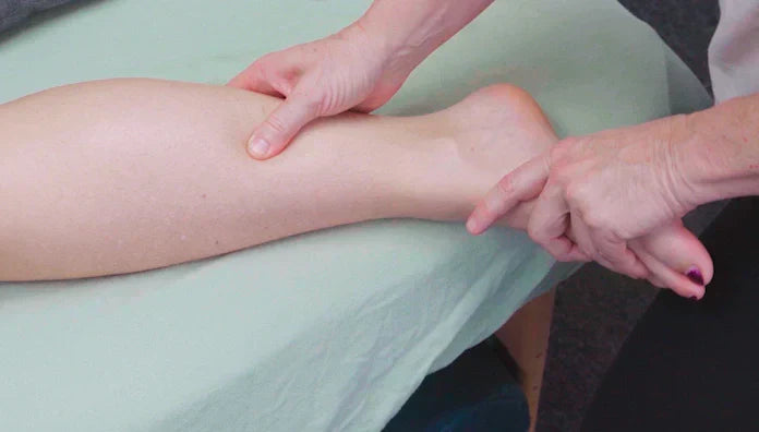 Therapist performing focused shin splint massage along the medial tibia to address medial tibial stress syndrome (MTSS)